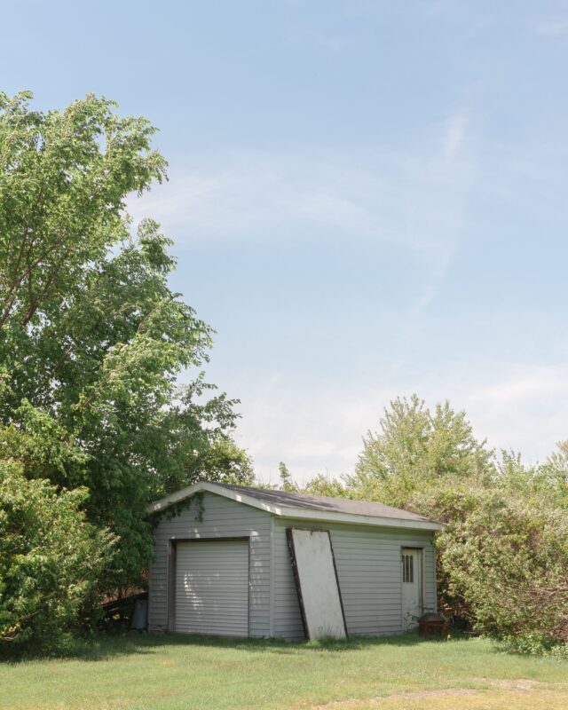 White wooden backyard storage shed under a clear blue sky